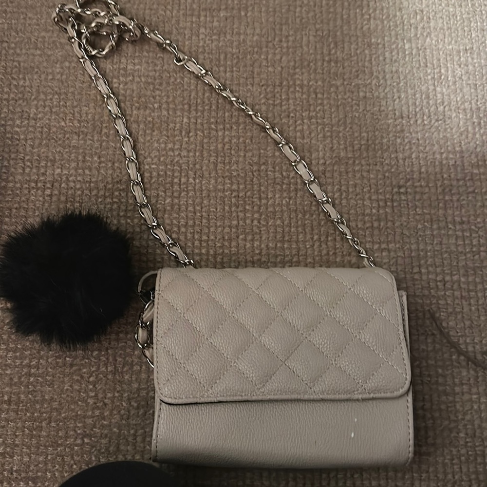 Tan crossbody bag with black puff ball keychain